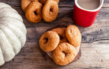 Homemade pumpkin donuts, on a rustic wooden background, illuminated with natural light.