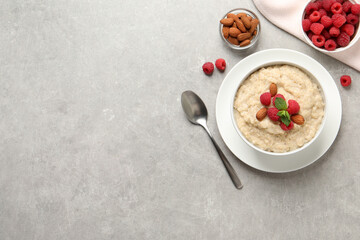 Tasty oatmeal porridge with raspberries and almond nuts served on light grey table, flat lay. Space for text