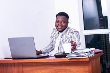 adult businessman holding a cup of coffee at the office smiling.