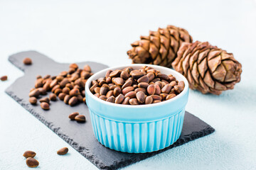 A bowl of unpeeled pine nuts and pine cones on a slate board. Detox and cure for insomnia. Healthy...