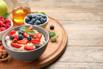 Tasty oatmeal porridge with berries and almond nuts served on wooden table, space for text