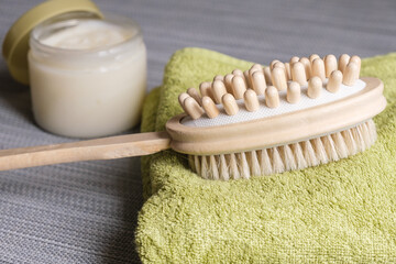Obraz na płótnie Canvas Double-sided massage brush for body brushing lies on towel on background body scrub. Pins of natural wood for removing of cellulite and stimulating your lymphatic system. Materials for spa treatments