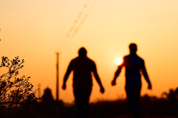 Fototapeta na wymiar Unfocused but focused pic of 2 persons while walking in beautiful sunrise or sunset