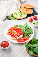 Delicious bagel stuffed with feta, tomatoes and pumpkin seeds and spinach leaves on a plate. Light Healthy Vitamin Snack. Vertical view
