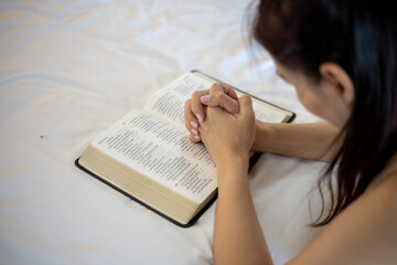 Woman hand praying on holy bible in the morning. Study bible with online worship.