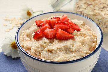 Tasty oatmeal porridge with strawberries on table, closeup