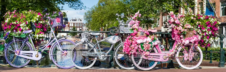 Poster de jardin Amsterdam Amsterdam, Fahrräder auf einer Brücke mit Blumen bei den Grachten in Holland, ein Panorama.