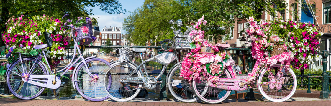 Amsterdam, Fahrr&auml;der auf einer Br&uuml;cke mit Blumen bei den Grachten in Holland, ein Panorama.