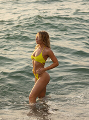 Sexy beautiful woman in yellow bikini on the beach.
