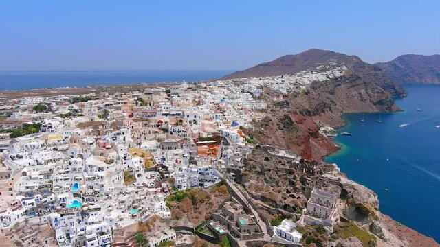 Santorini, Greece: Aerial view of Oia, famous village with iconic white houses on Thira (Thera) island, caldera cliffs towering over Mediterranean Sea - landscape panorama of Europe from above
