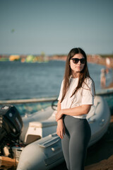 Fototapeta na wymiar Young woman on the beach with long hair. Fit beautiful girl wears white shirt and gray leggings on the beach
