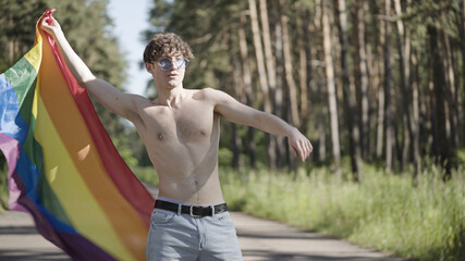 Topless young man waving with rainbow flag, supporting lgbt rights, pride parade