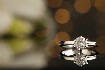 Beautiful engagement ring against blurred festive lights, closeup. Space for text