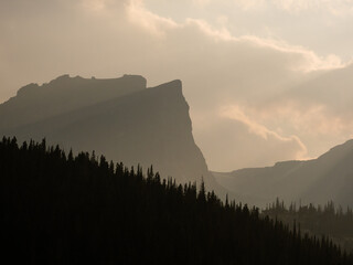 Landscape of forest silhouette and dramatic light shining on ridges of Rock Mountains.