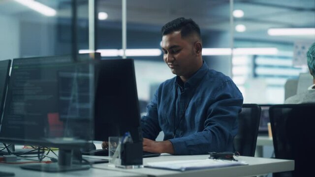 In Diverse Office: Portrait of Handsome Indian Man Working on Desktop Computer. Focused Professional Creates Innovative Software, Modern App Design. Stylish Multi-Ethnic Authentic Workplace
