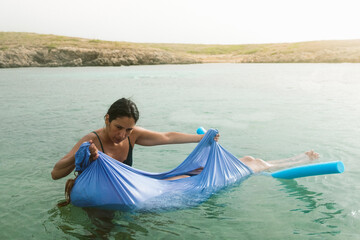 women floating an relaxing with water shawl in the calm sea at sunset with pool noodle and shawl, a new healing and relaxing technique