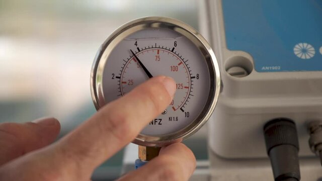 Pressure gauge meter in smart farm. hand touching Pressure of fluid measured in units of force per unit of surface area. The water meter shows farm consumption of water. PSI, close up