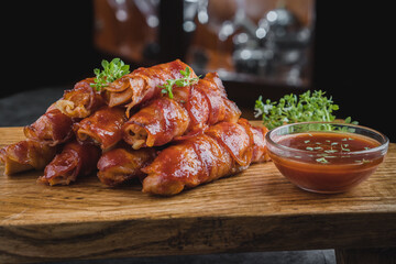 Chicken fingers rolled up of bacon with some bbq sauce