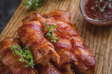 Chicken fingers rolled up of bacon with some bbq sauce