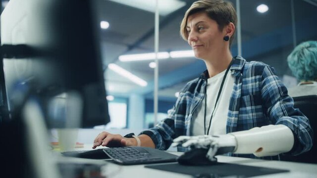 Diverse Body Positive Office: Portrait of Motivated Woman with Disability Using Prosthetic Arm to Work on Computer. Brave Professional with Futuristic Body Powered Myoelectric Bionic Hand