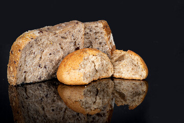 Healthy organic,  bread made of whole rye and wheat flour, and seeds on black reflective background. Close up view.