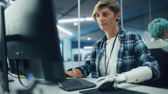 Diverse Body Positive Office: Portrait of Motivated Woman with Disability Using Prosthetic Arm to Work on Computer. Brave Professional with Futuristic Thought Controlled Myoelectric Bionic Hand
