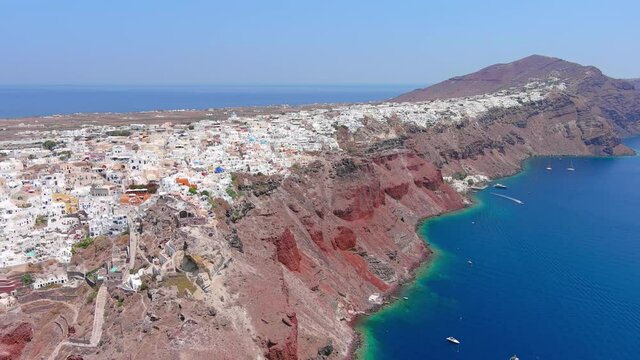 Santorini, Greece: Aerial view of Oia, famous village with iconic white houses on Thira (Thera) island, caldera cliffs towering over Mediterranean Sea - landscape panorama of Europe from above
