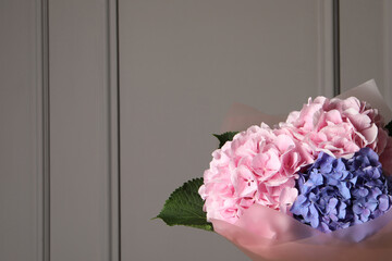 Bouquet of beautiful hortensia flowers near grey wall. Space for text