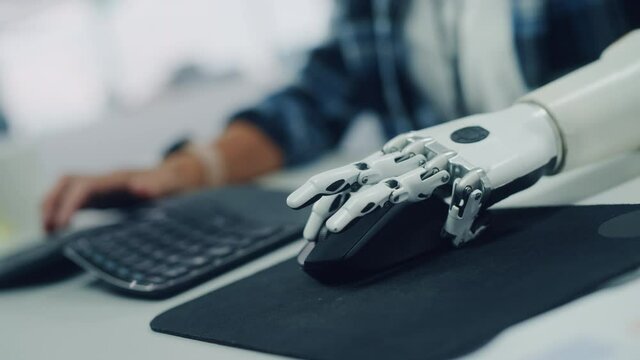Inclusive Office: Person with Disability Using Prosthetic Arm to Work on Computer. Professional with Advanced Myoelectric Bionic Limb to Control Mouse. Focus on Hands with Stylish Dutch Angle Shot