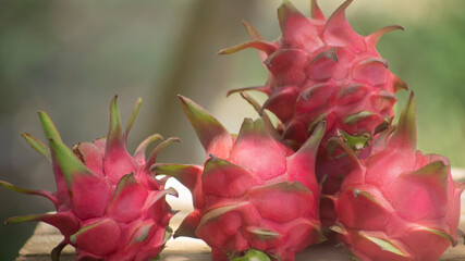 red pitahaya or dragon fruit on wooden table outdoors with blur background and space for text