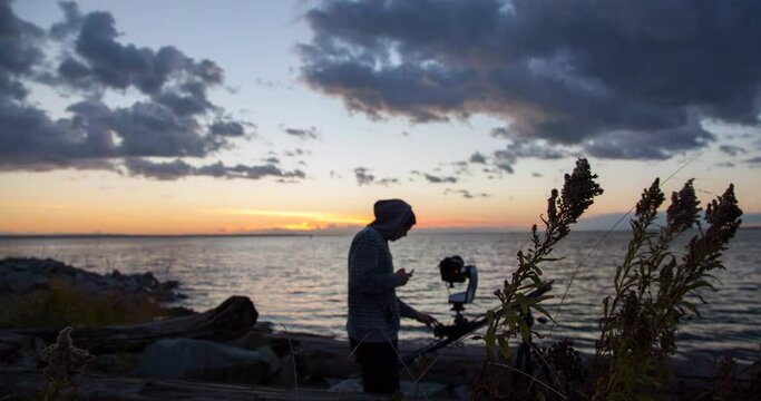 Time Lapse Shot Of Man Recording Sea With Camera Set Up On Landscape During Sunset - Vancouver, Canada