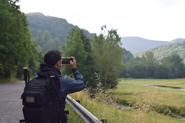 Chico joven haciendo una foto al paisaje con su m&oacute;vil