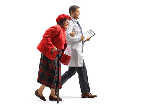 Full Length Profile Shot Of A Young Male Doctor Walking And Holding An Elderly Woman Under Shoulder