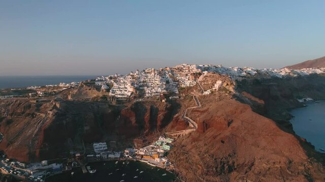 Aerial video of a drone on Santorini island, Oia city at sunset, popular wedding venue and gorgeous photo locations for social media, the famous windmill in Santorini