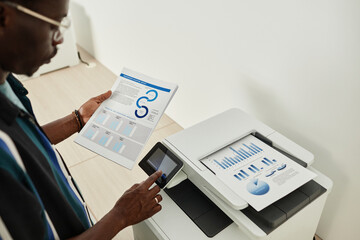 Serious entrepreneur printing out annual reports for meeting with coworkers