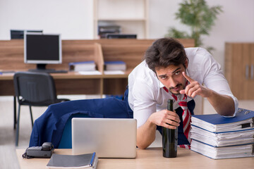 Young alcohol addicted male employee working in the office