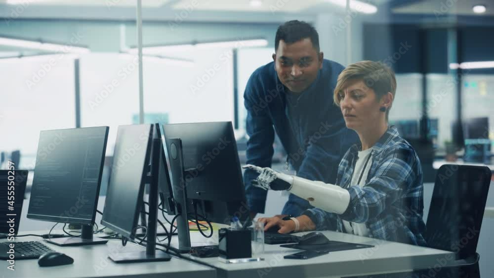 Poster Teamwork In Diverse Inclusive Office: Project Manager Talks with Woman with Disability with Prosthetic Arm to Work on Desktop Computer. Professionals Software Engineers Create e-Commerce App Solution