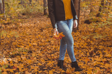 Close-up of woman is kicking yellow leaves in autumn. Sad mood and seasonal affective disorder...