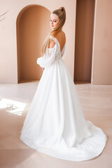 Fototapeta premium Perfect bride, portrait of a girl in a long white dress. Beautiful hair and clean delicate skin. Wedding hairstyle blonde woman. 