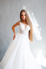 Fototapeta na wymiar Perfect bride, portrait of a girl in a long white dress. Beautiful hair and clean delicate skin. Wedding hairstyle blonde woman. 