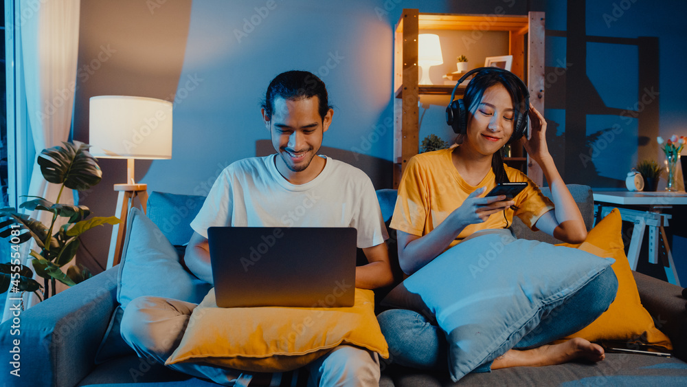 Wall mural freelance asia couple man and woman in casual hasband work laptop computer at night enjoy happy rela