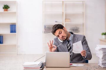 Fototapeta premium Young male employee unhappy with excessive work in the office