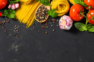 Italian food ingredients with pasta, tomatoes, pepper, garlic and parsley on dark background with...