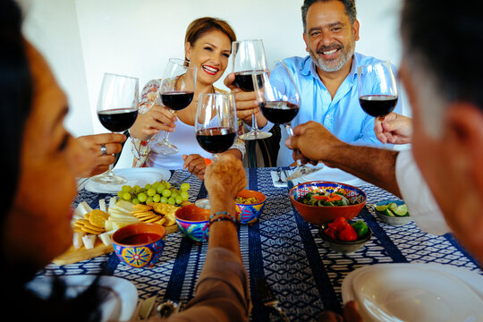 Cheerful family toasting wineglasses at table during weekend together