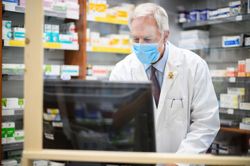 Pharmacist at work with a computer in his store