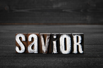 Savior. White wooden letters on a dark wooden background