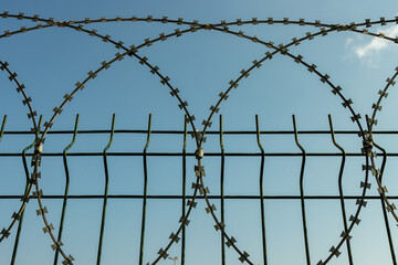 Knitted against illegal passage of people, refugees and immigrants at the country border barbed wires against a fence