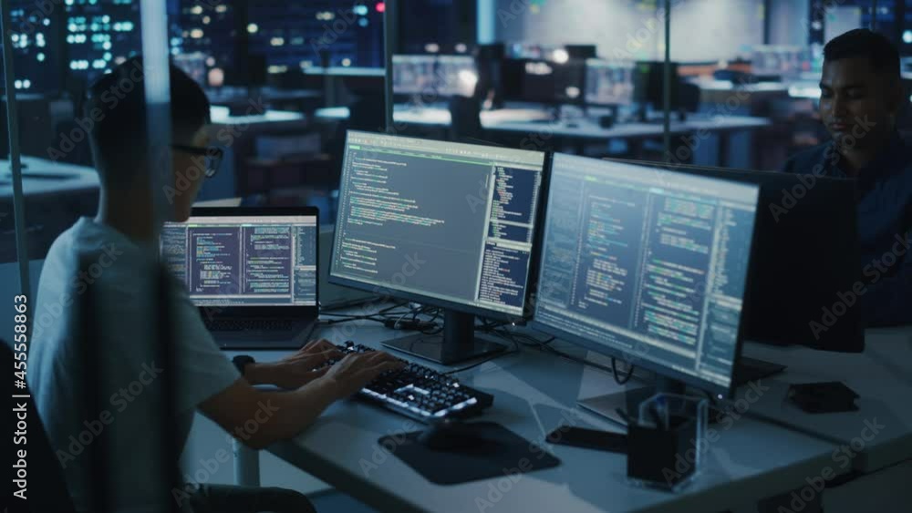 Poster Night Office: Young Japanese Man in Working on Desktop Computer. Diverse Multi-Ethnic Team of Programmers Typing Code, Creating Modern Software, e-Commerce App Design, e-Business Programming. Arc Shot