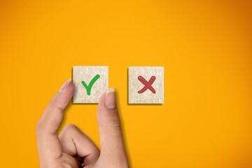 Right and wrong icons on wooden cubes with hand choosing the right icon