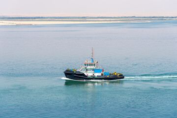 Tug boat sailing through Grate Bitter Lake. She assists to the cargo ships transiting Suez Canal. 